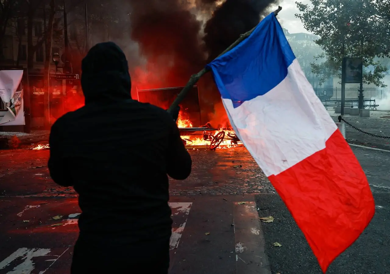 Un manifestante que lleva una bandera francesa se enfrenta a la policía en la Place de la Madeleine durante una manifestación
