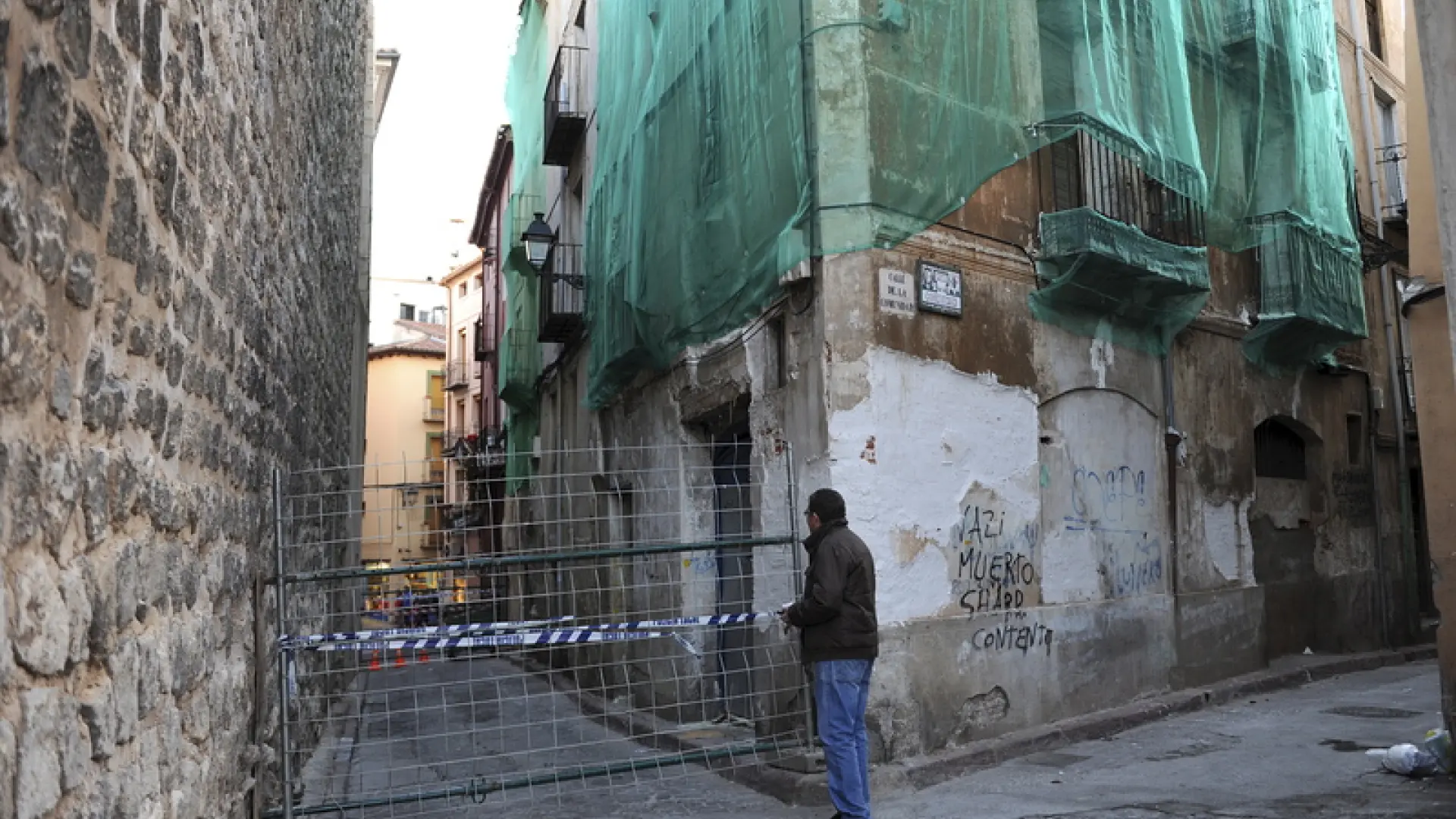 Casas ruinosas situadas frente a un torreón medieval.