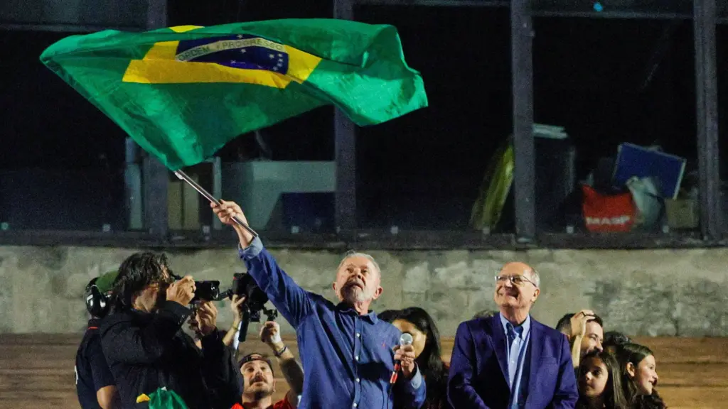 El presidente de Brasil, Luiz Inácio Lula da Silva, ondea una bandera brasileña mientras se dirige a sus seguidores tras su v