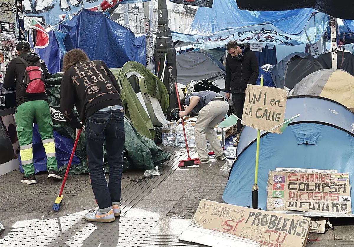Varias personas limpian en la acampada de la Puerta de Sol, este sábado. Varias personas limpian en la acampada de la Puerta